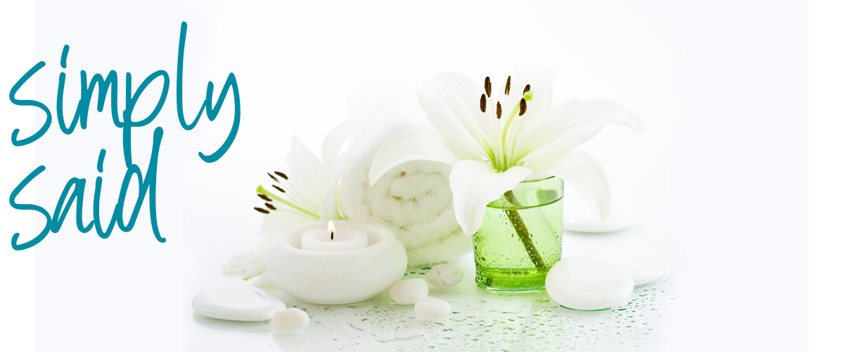 white candles with white lilies in green vase and white towel in background
