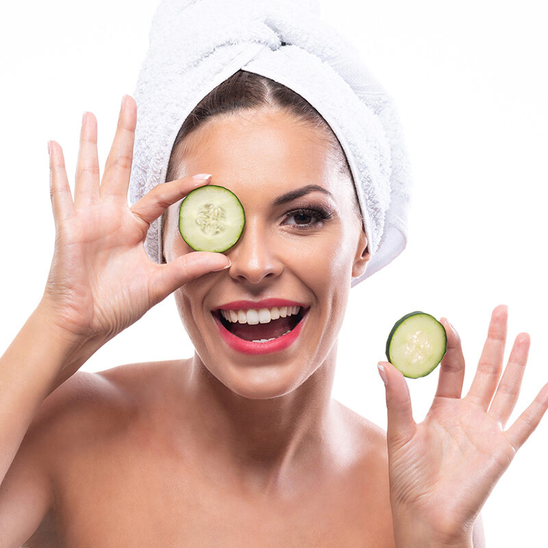 woman with cucumber on left eye smiling